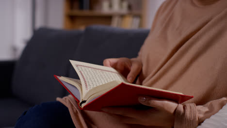 Nahaufnahme-Einer-Muslimischen-Frau,-Die-Zu-Hause-Auf-Dem-Sofa-Sitzt-Und-Den-Koran-Liest-Oder-Studiert-5